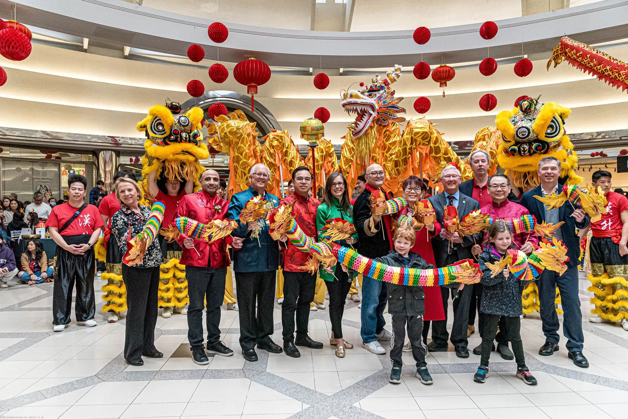 Community members and Hon Hsing performers celebrating Lunar New Year with lion and dragon dance under red lanterns